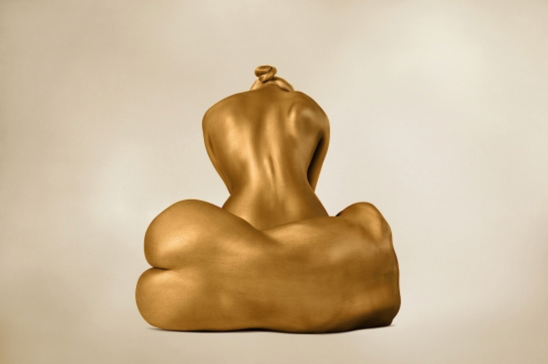 Gold-painted figure viewed from behind in a compact sculptural pose, photographed by Zack Zublena and selected by Duncan Miller Gallery.