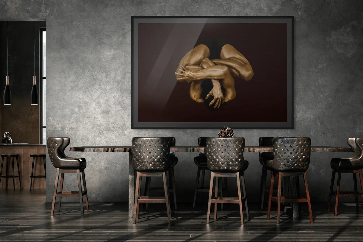 Golden-painted human figure in an intertwined, protective posture by Zack Zublena, fine art photography framed on a dark wall in a luxury dining room
