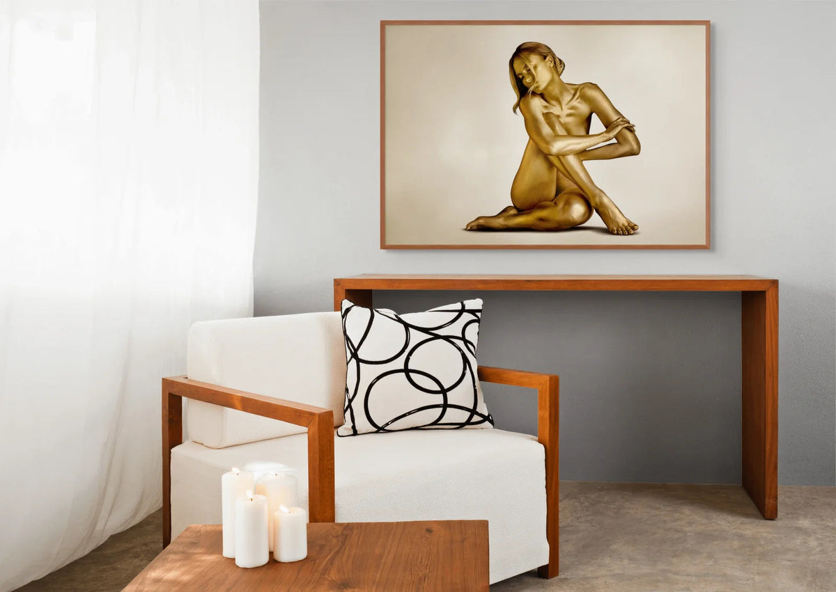 Seated gold-painted figure, fine art photograph by Zack Zublena above a wooden console in a calm, light-filled Seattle interior
