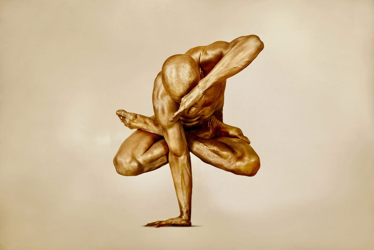 Rising Above by Zack Zublena - Fine art photography of a golden body-painted male artist in an artistic balancing pose