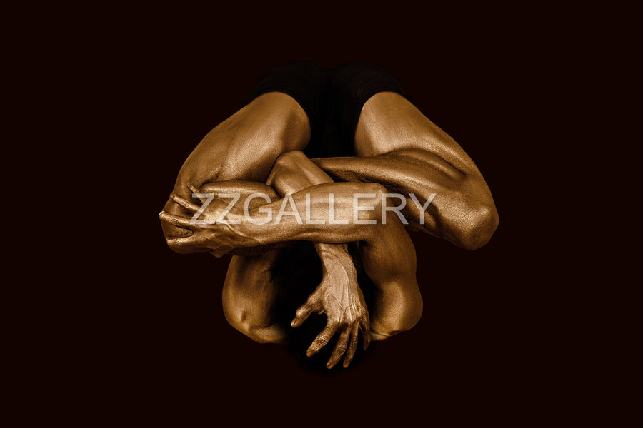 Golden-painted nude body folded in a compact meditative pose, symbolizing ego dissolution and consciousness expansion. Contemporary fine art photography by Zack Zublena.