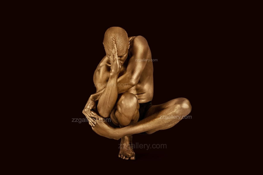 Golden-painted male figure in a defensive seated pose, fine art photography from Zack Zublena’s Midnight Bronze Collection, titled “Centurion’s Oath.”