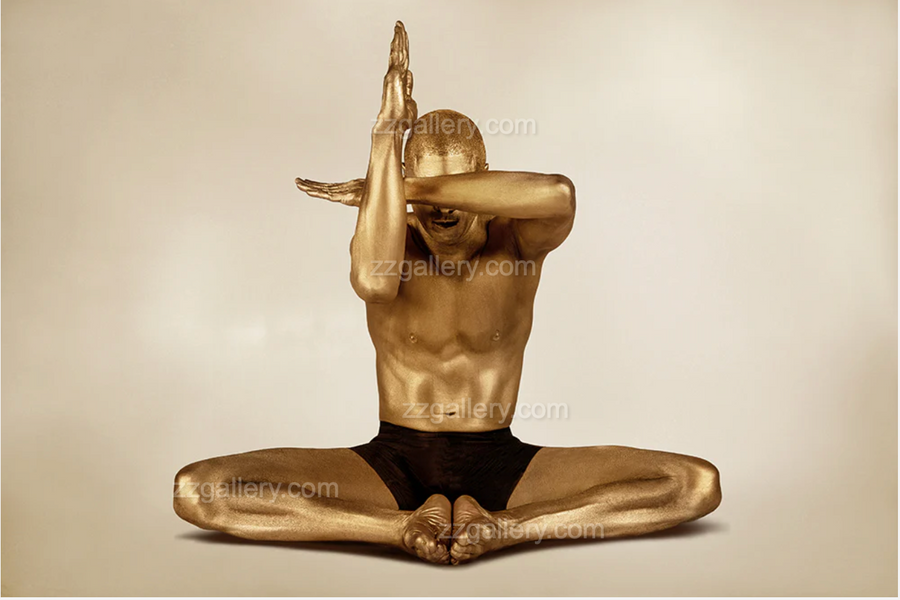 Gold-toned figure in an abstract meditation pose, arms folded in front of face, fine art photograph.