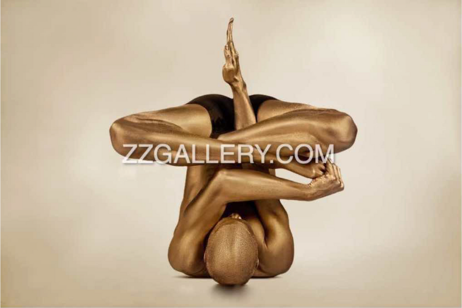 Golden-painted yoga figure in a complex yoga pose, arms and legs entwined, captured as contemporary fine art photography symbolizing transformation and emergence.