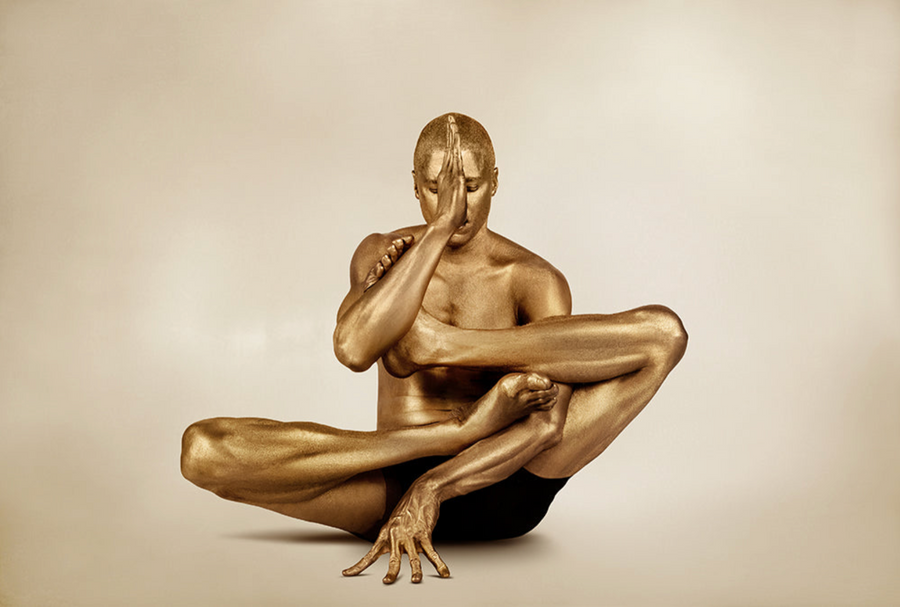 Golden-painted male figure in a sculptural yoga pose with hand to face, captured as fine art photography. Ideal for yoga studios, meditation rooms, luxury interiors, and modern art collections.