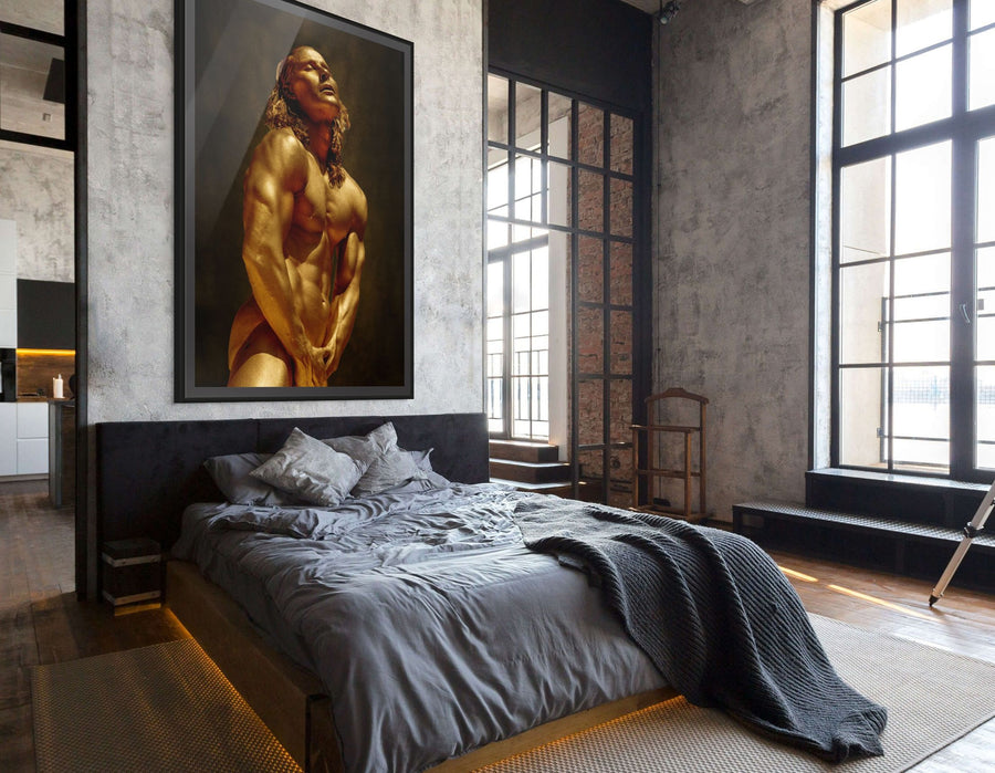 Golden masculine figure wall art – fine art photography of a powerful male form painted in shimmering gold tones, displayed as luxury décor in a modern bedroom interior.