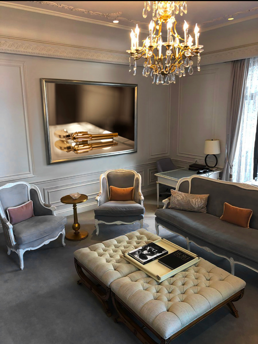 Golden revolver luxury wall art by Zack Zublena displayed in an elegant living room interior with chandelier and classic decor.