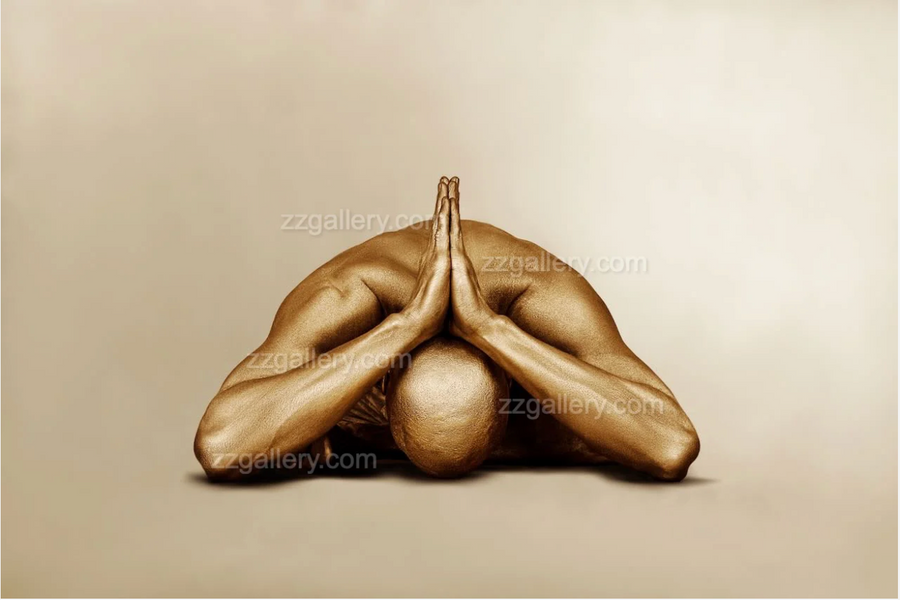 Gold-painted figure in a forward prayer yoga pose, wall art in a cozy wooden cabin interior.