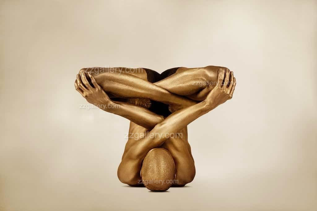 Golden-painted figure folded in a crossed-body yoga pose, conceptual fine art photograph by Zack Zublena symbolizing transcendence and quantum field awareness.
