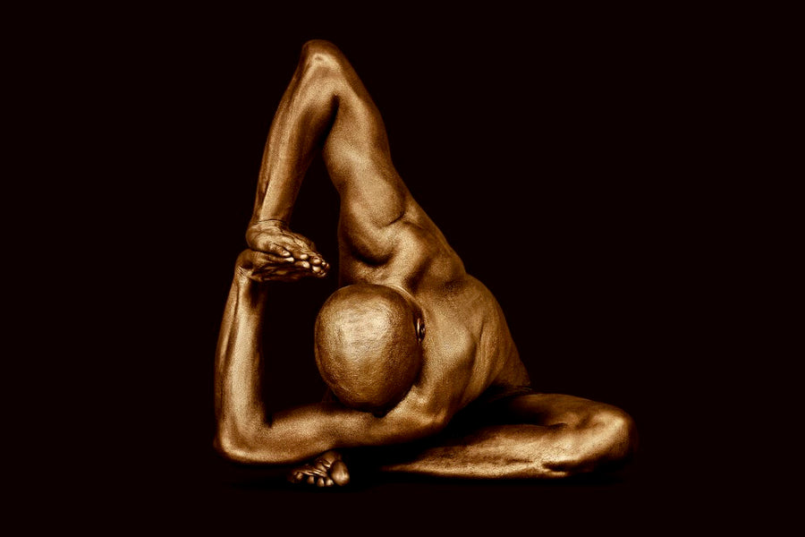 Gold-painted male figure in a deep side stretch pose, arms extended gracefully, displayed against a dark background. Contemporary fine art wall photography by Zack Zublena.