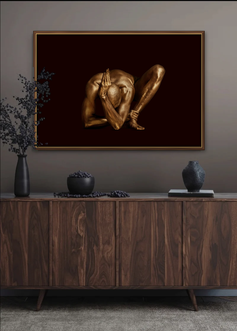 "Salutation to the Sun" by Zack Zublena: a limited edition gold body paint fine art photograph in a walnut and gold frame, hanging above a dark walnut sideboard in a warm grey interior with black vases and berry branches.