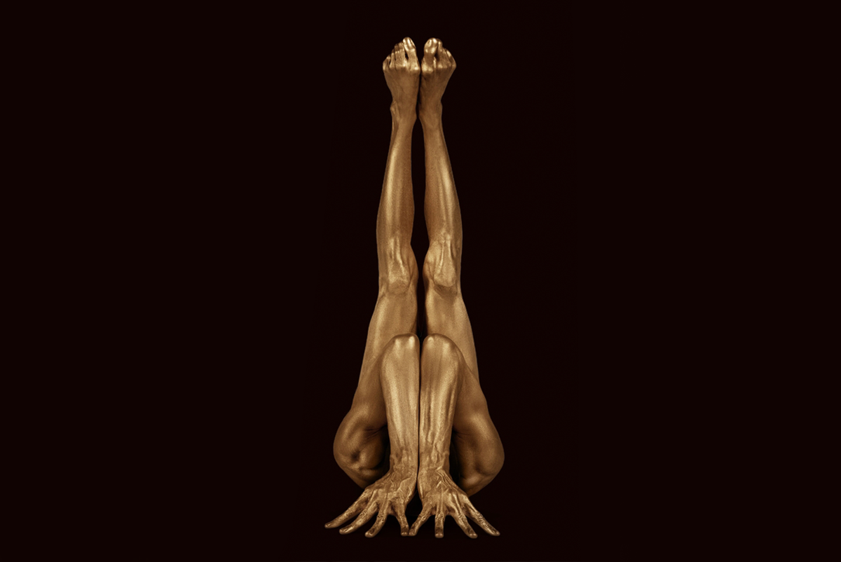 Gold-painted figure in a symmetrical inverted sculptural pose, photographed by Zack Zublena and featured by Duncan Miller Gallery.