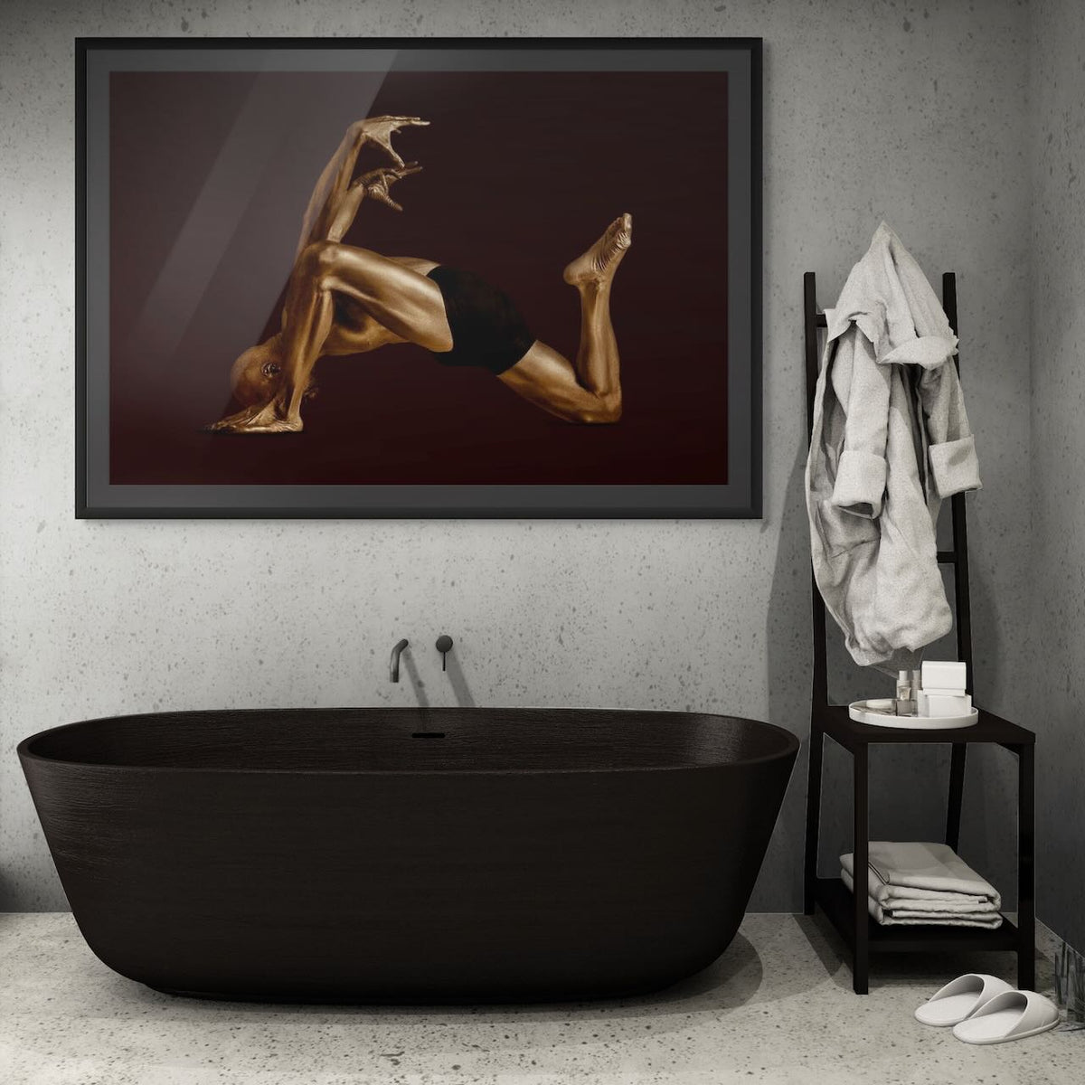 Gold-painted figure in a dynamic pose, fine art photograph by Zack Zublena above a black freestanding bathtub in a minimalist concrete spa bathroom