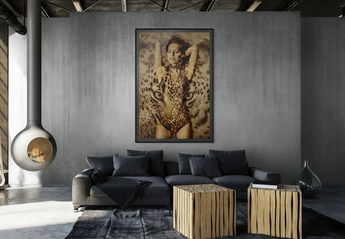 Gold fine art photograph by Zack Zublena: a figure with arms raised covered in leopard rosettes, framed above a dark sofa in an industrial loft with a hanging fireplace