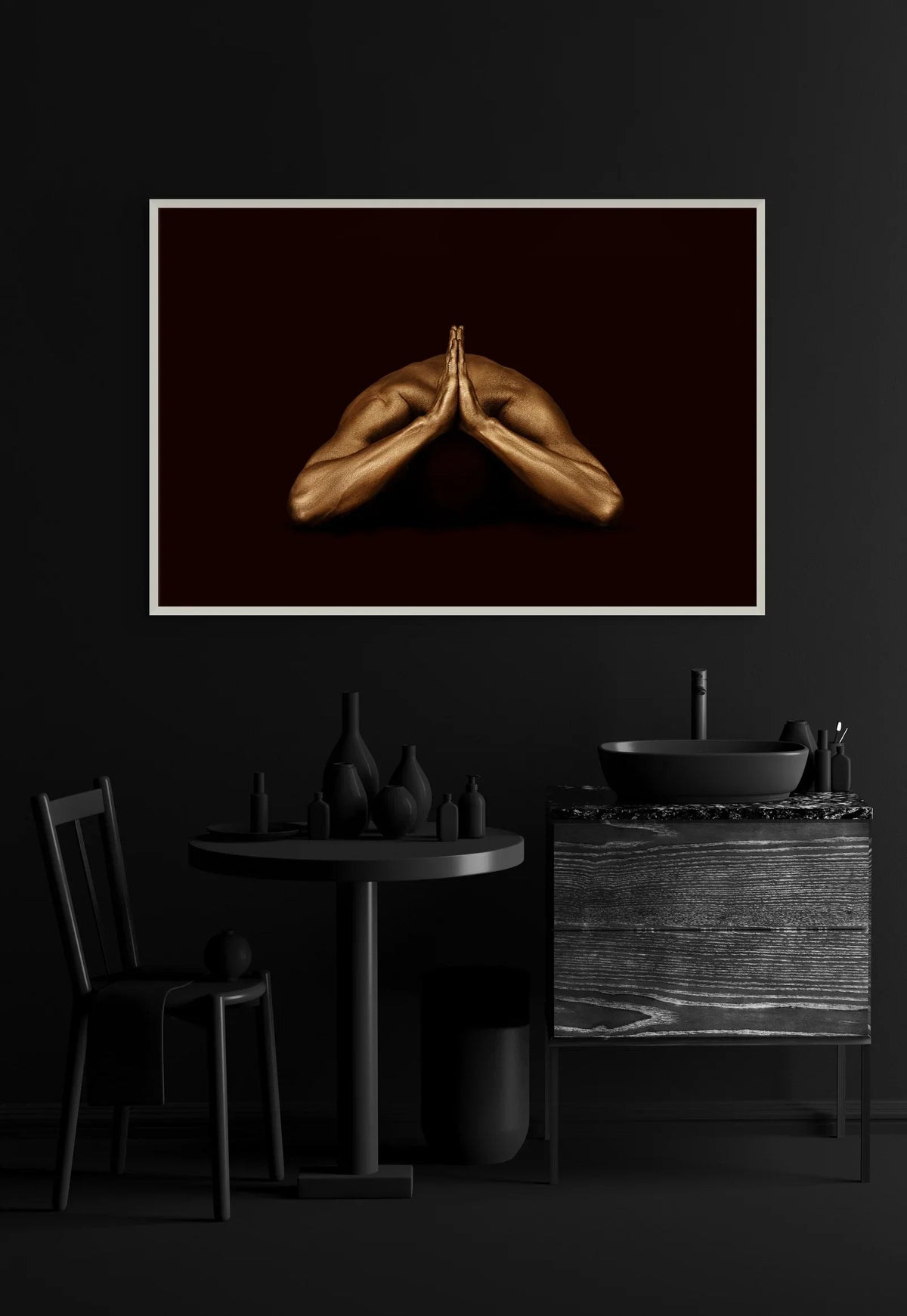 Gold-painted hands in prayer pose on a black background, landscape fine art print by Zack Zublena in a white frame on a dark moody wall above a black table and chair