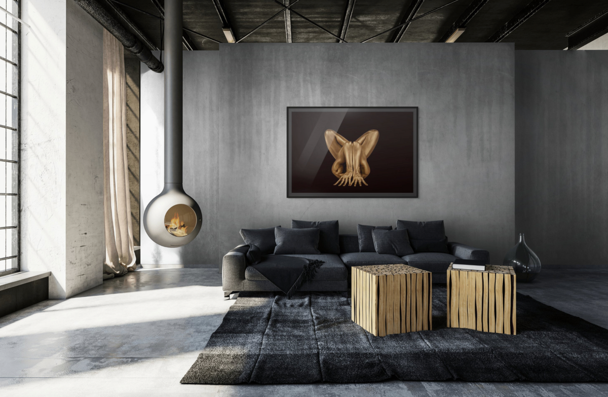 Interior mockup featuring Hidden Horus by Zack Zublena, a photograph of a gold-painted figure displayed above a charcoal sofa beside a suspended fireplace.