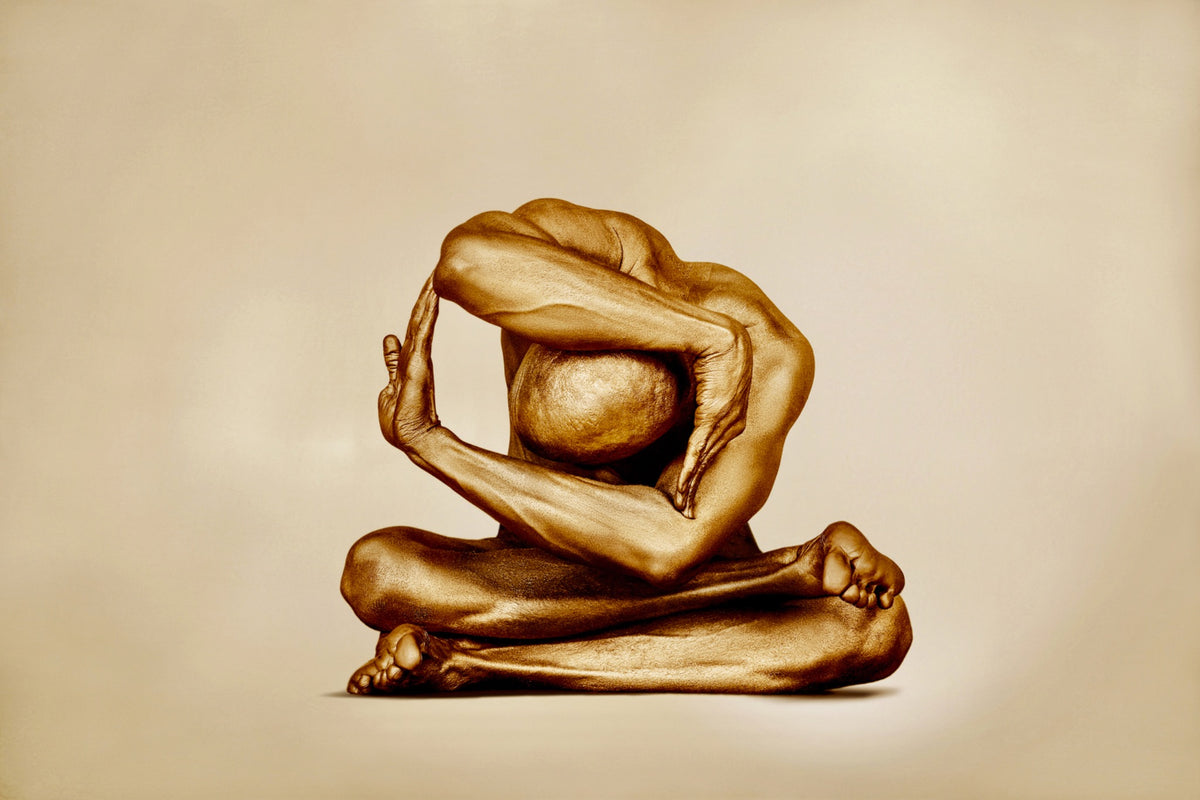 Fine art photography print titled 'Anatomy of Resistance' by Zack Zublena, featuring a human figure painted in luminous gold in a dynamic, sculptural seated pose against a warm neutral background.