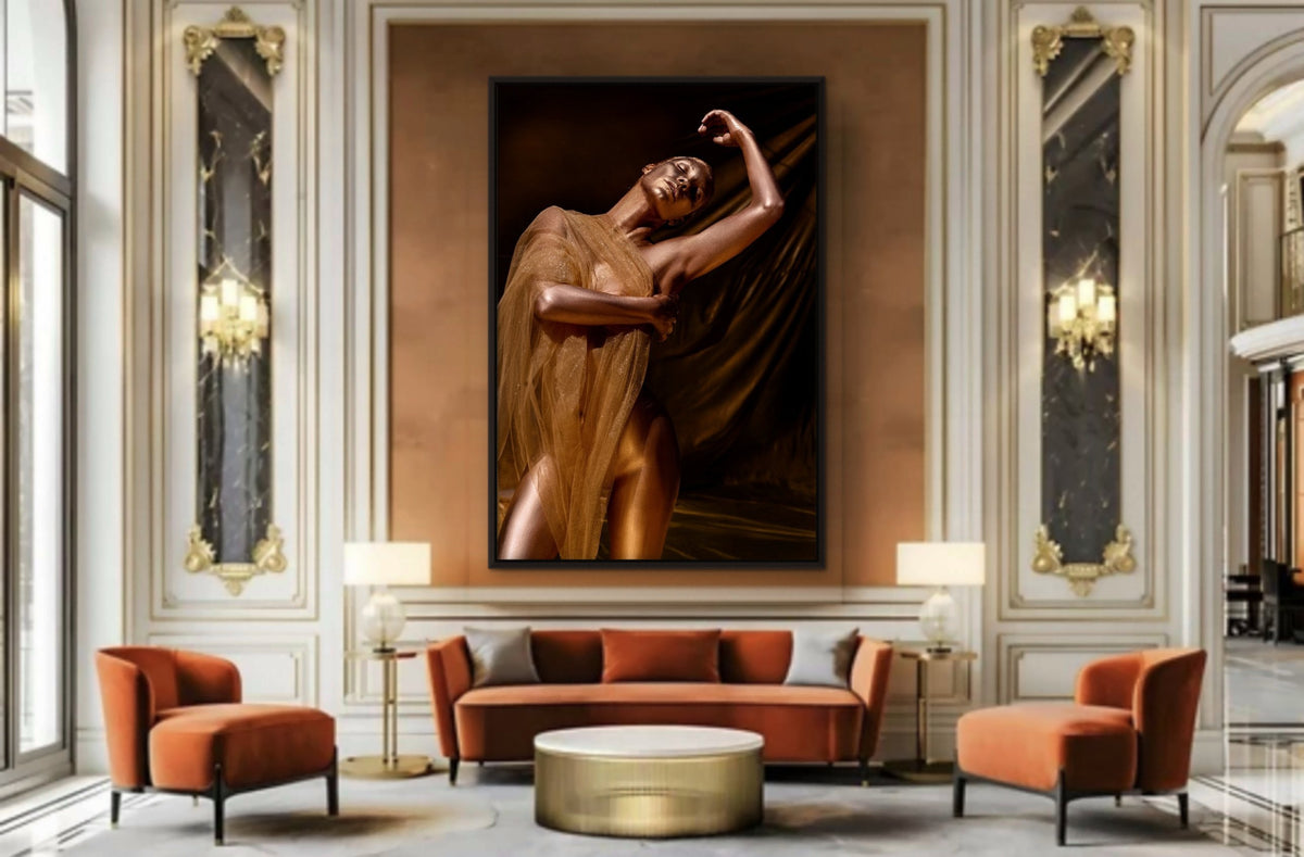 Golden Draped Figure by Zack Zublena, a gold-painted woman in a sheer golden veil with one arm raised, fine art photography in a thin black frame above an orange velvet sofa in a luxury Parisian-style salon