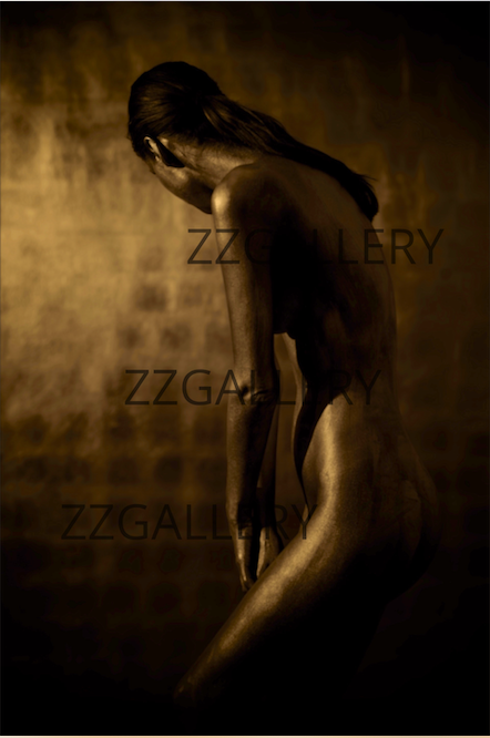 Gold and silver-painted nude female figure in bowed pose, fine art photography capturing introspection and divine feminine stillness