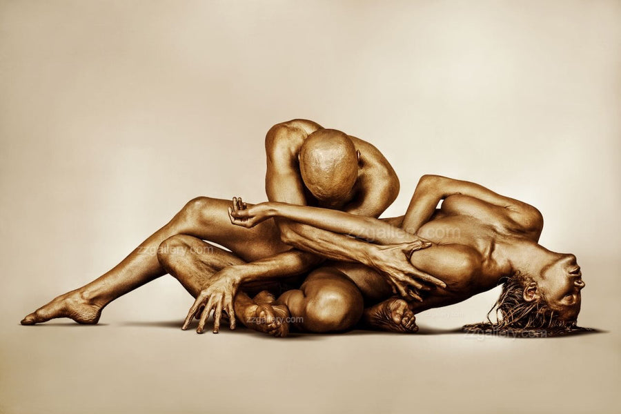 Golden-painted nude couple in a sacred surrender pose, fine art wall photography displayed in a luxury modern living room above a fireplace — elegant gold body art decor for spas, wellness retreats, and sophisticated interiors.