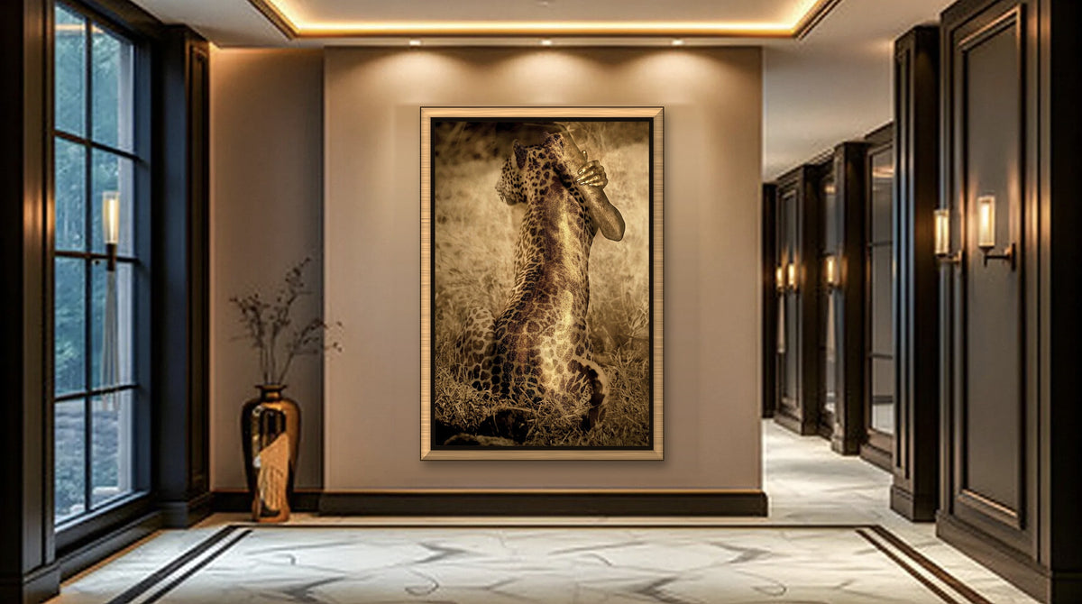 "Unveiled Instinct" by Zack Zublena: leopard art fine art photograph of a woman painted in gold, in a champagne gold frame with a black inner liner, on the wall of a luxury hallway with dark wood panelling and warm cove lighting.