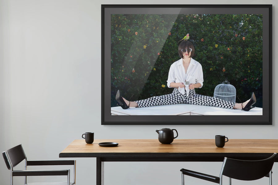 Whimsical surreal fine art photograph Coffee Time by Zack Zublena, featuring a woman in checkerboard pants sipping coffee with a bird on her head.