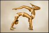 Two women painted in gold performing an acrobatic yoga pose in perfect balance, fine art photography for luxury wall decor