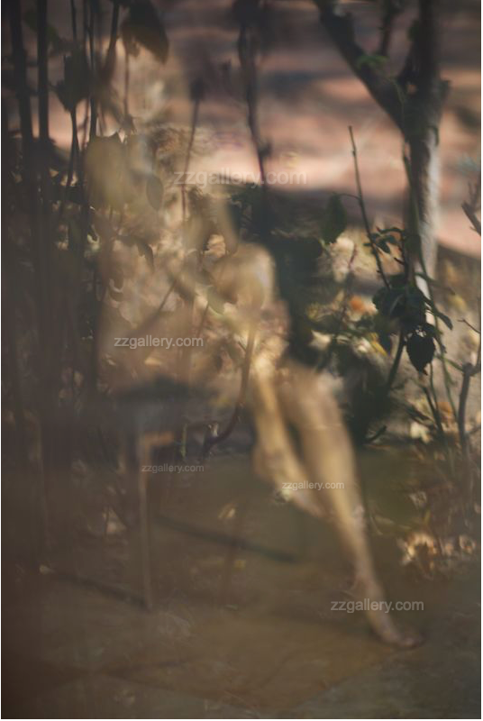Golden-painted feminine figure in soft-focus fine art photograph, framed and displayed in a serene yoga studio with natural light and plants.