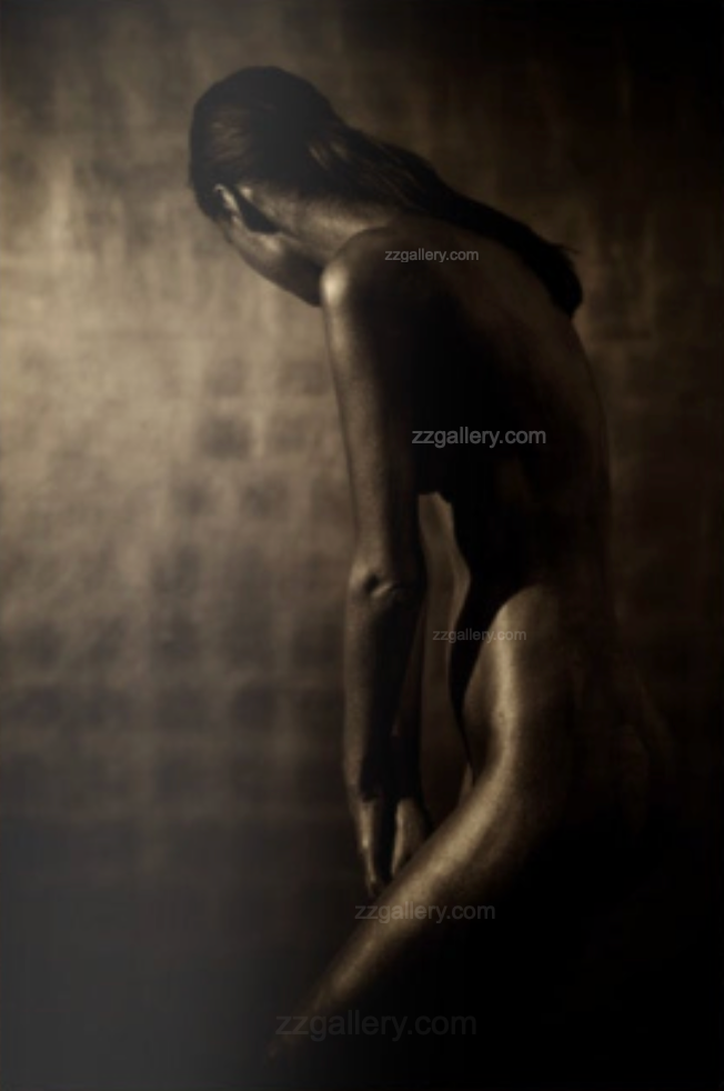 Gold and silver-painted  figure in bowed pose, fine art photography capturing introspection and divine feminine stillness