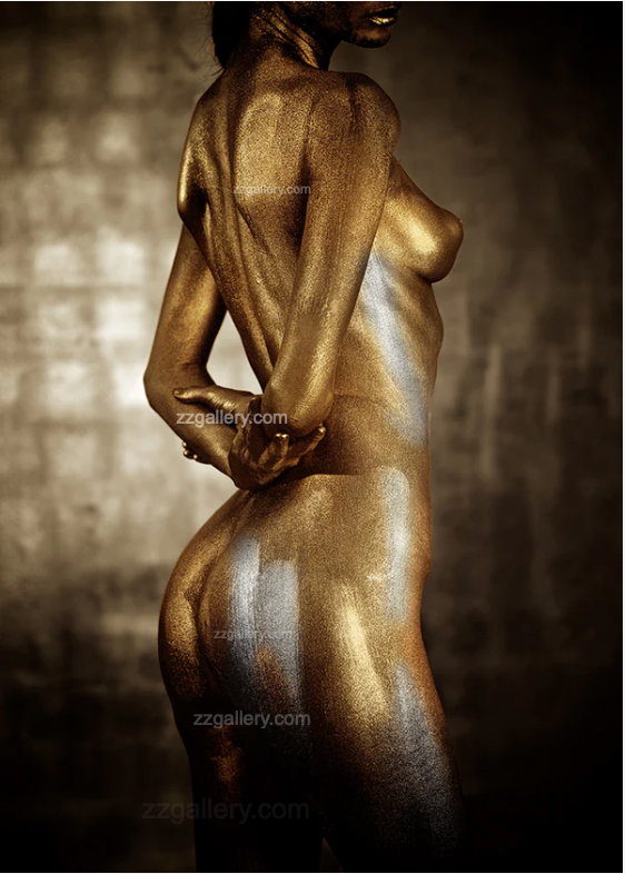 Golden-painted nude female figure with silver tones, viewed from the back, displayed as luxury wall art in a modern staircase interior with marble and fireplace.