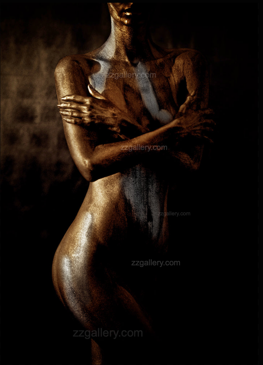 Golden nude fine art photograph of a female figure with shimmering gold and silver body paint, displayed above a black marble fireplace in a luxury interior.