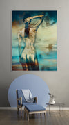 Golden-painted silhouette figure facing the ocean, contemporary fine art print displayed above a modern chair in a stylish living room.