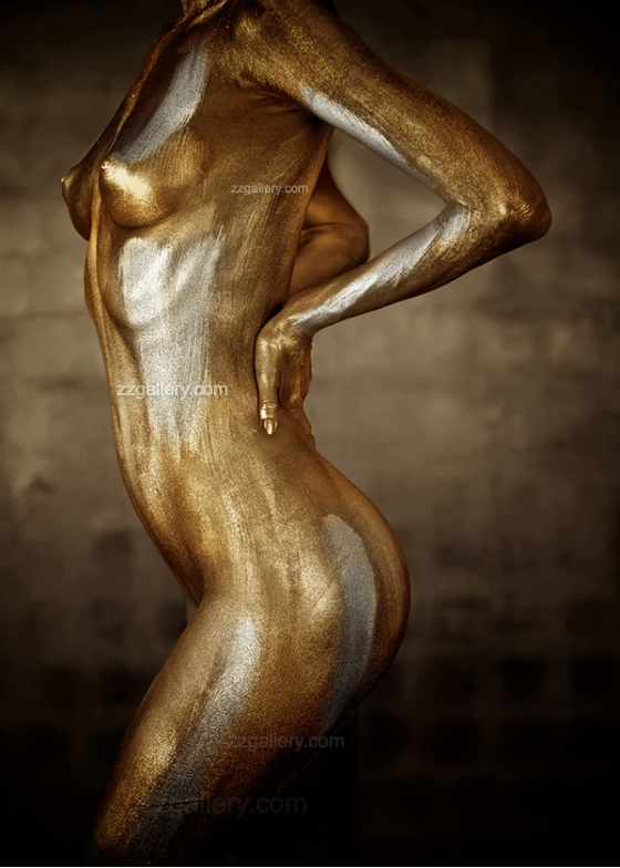 Golden and silver-painted figure in a sculptural pose, luxury fine art wall decor displayed in an elegant modern interior with wooden cabinet and dark ceramic accents.