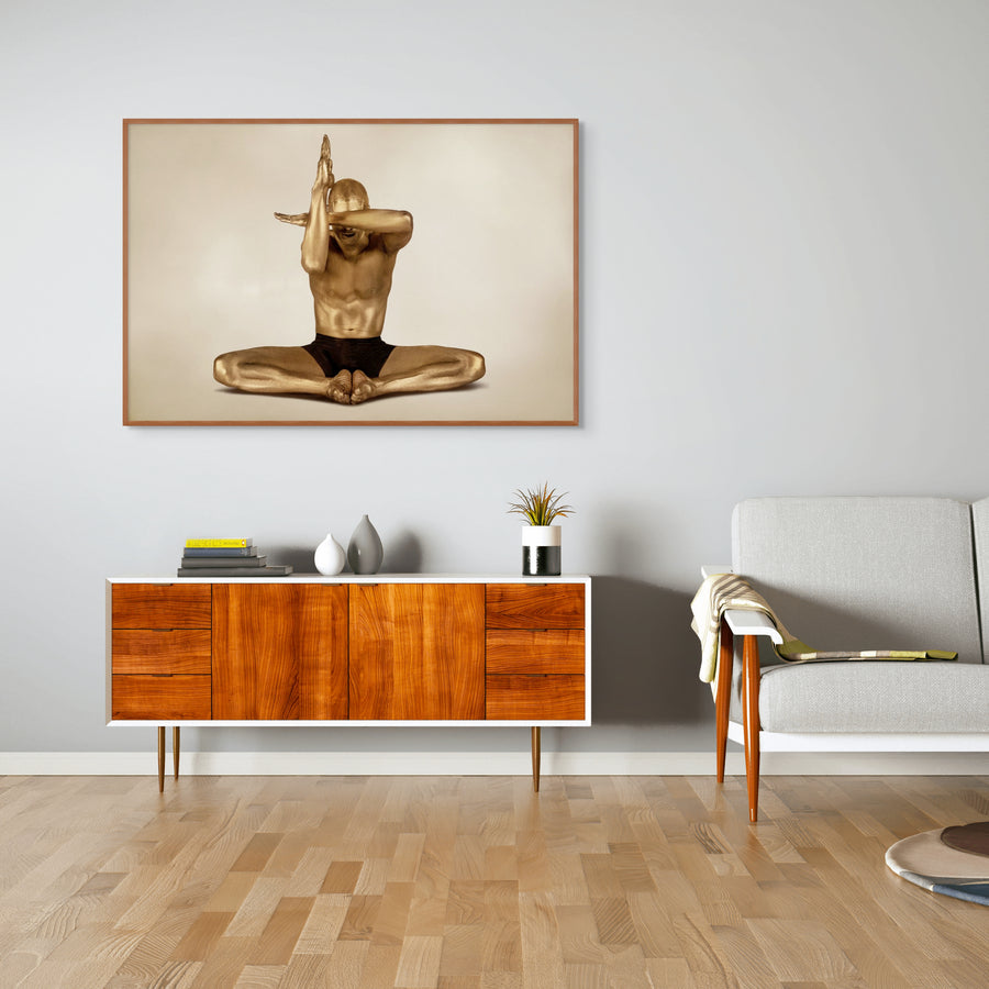 Gold-toned figure in an abstract meditation pose, arms folded in front of face, fine art photograph.