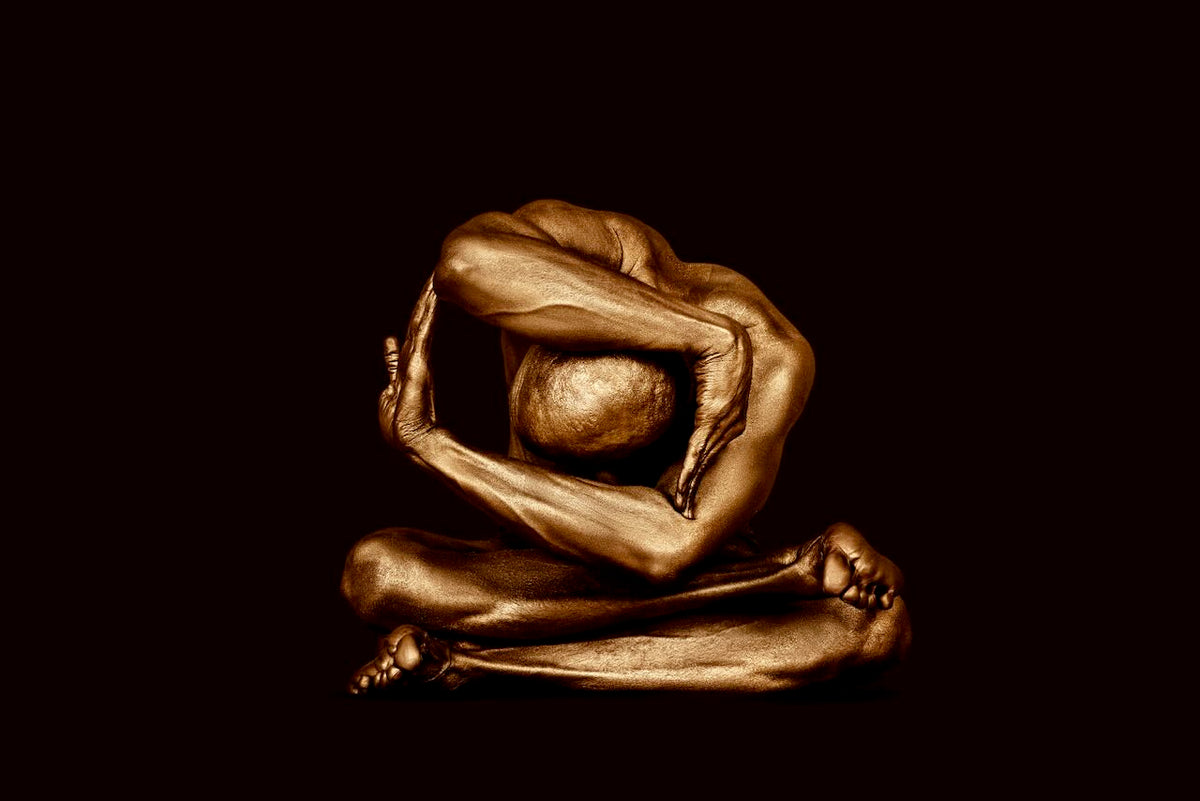 Figure masculine peinte en or dans une pose de yoga méditative avancée sur fond sombre, sculptée dans la symétrie et l'immobilité par Zack Zublena. Photographie d'art de luxe pour les intérieurs modernes, les salles de méditation, les spas et les collectionneurs.