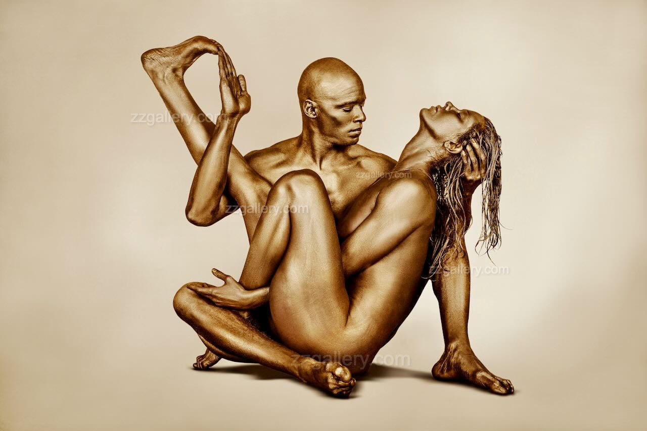 Golden-painted man and woman in a yoga-inspired union pose, luxury fine art photography for hotels, spas, and collectors.
