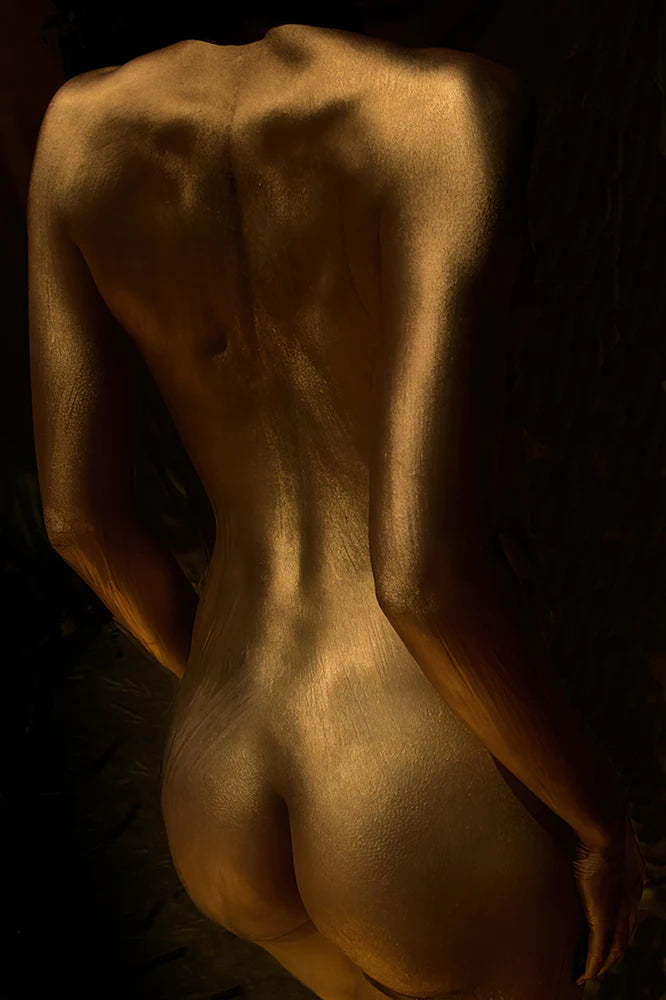 Elegant bedroom with a large framed artwork of a golden-painted female back. Sensual nude photography print radiating warmth and sophistication.