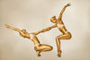 Gold-painted female duo in acrobatic balance pose, fine art photography for luxury hotels, spas, wellness spaces, and collectors.