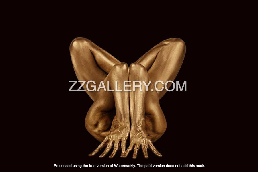 Gold-painted nude body folded in yoga lotus pose against beige background