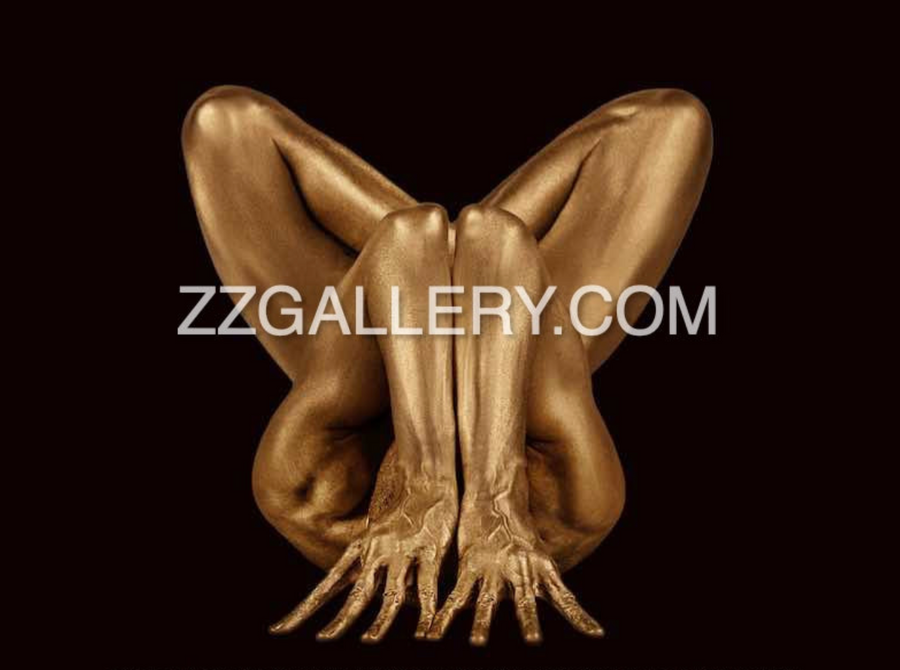 Gold-painted nude body folded in yoga lotus pose against beige background