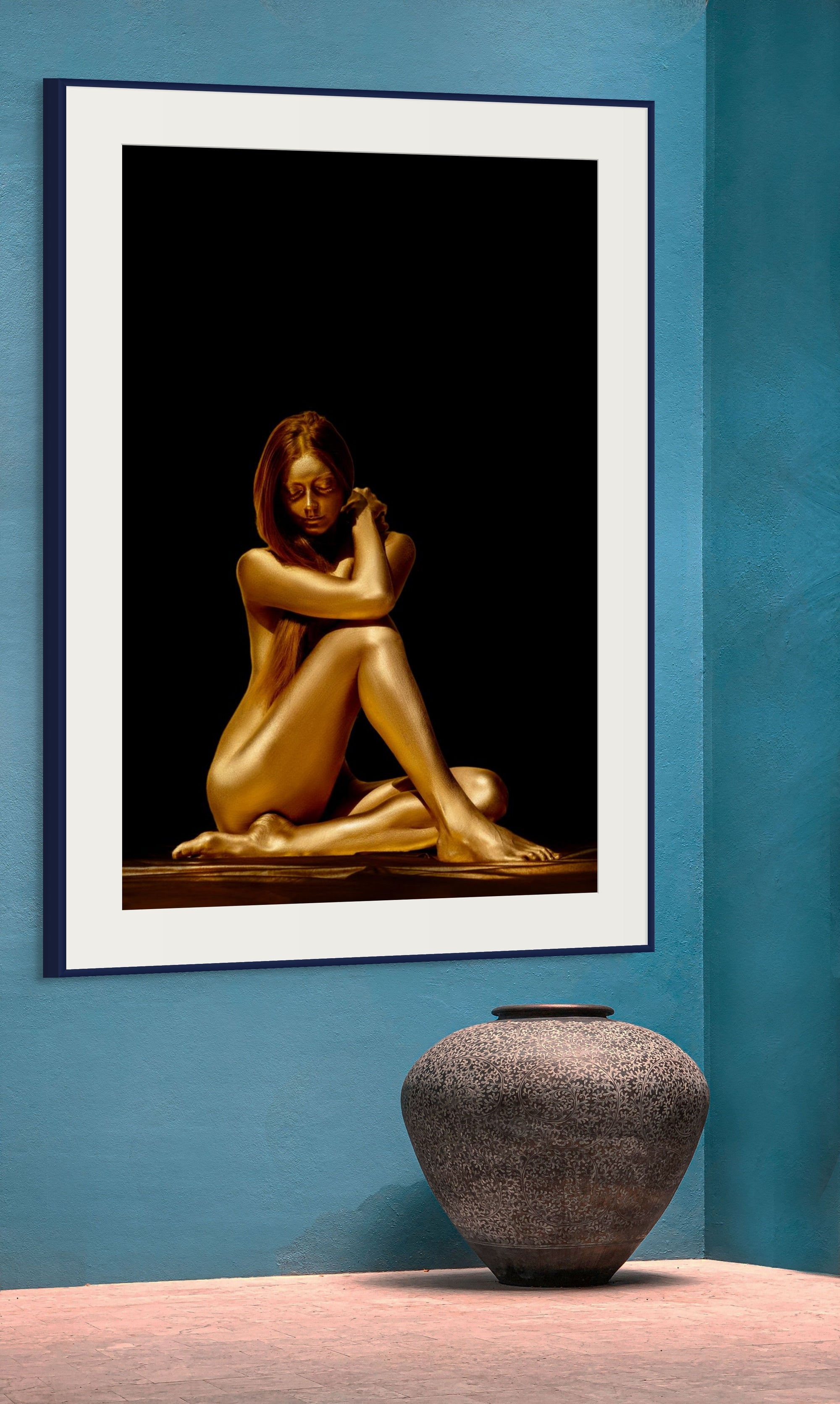 Golden-painted silhouette of a woman seated gracefully with arms wrapped around her knees, illuminated against a black background. Contemporary fine art photography symbolizing serenity, feminine elegance, and inner harmony — ideal for luxury interiors and modern wellness settings.