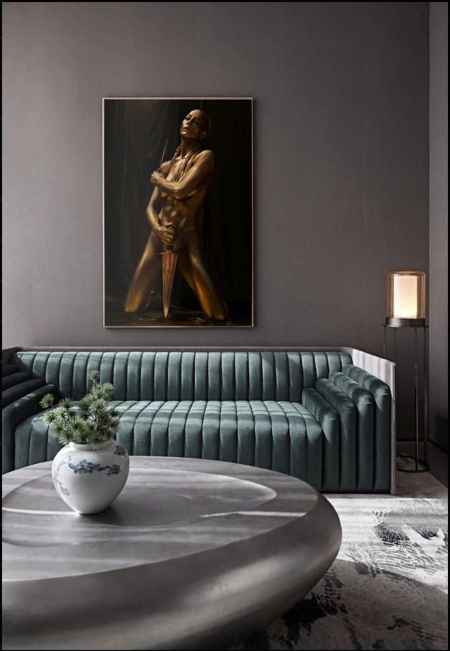 Golden-painted nude female warrior kneeling with sword, fine art photography celebrating sacred feminine strength and empowerment.