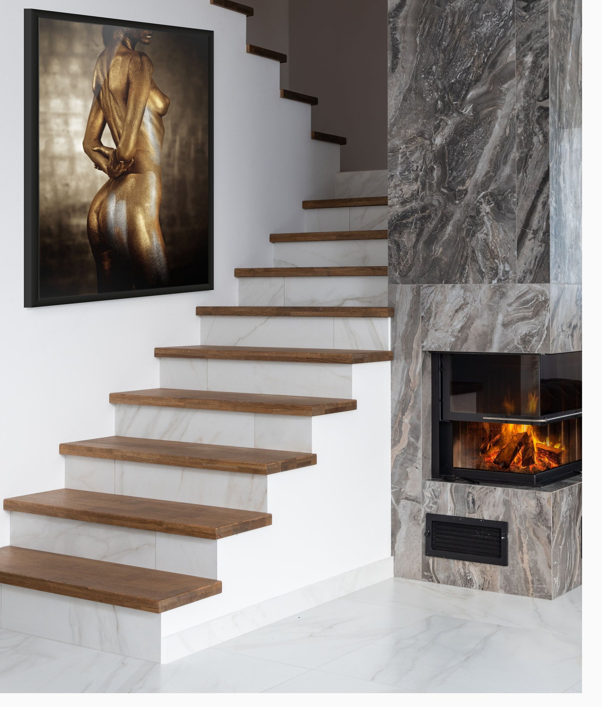 Golden-painted figure with silver tones, viewed from the back, displayed as luxury wall art in a modern staircase interior with marble and fireplace.