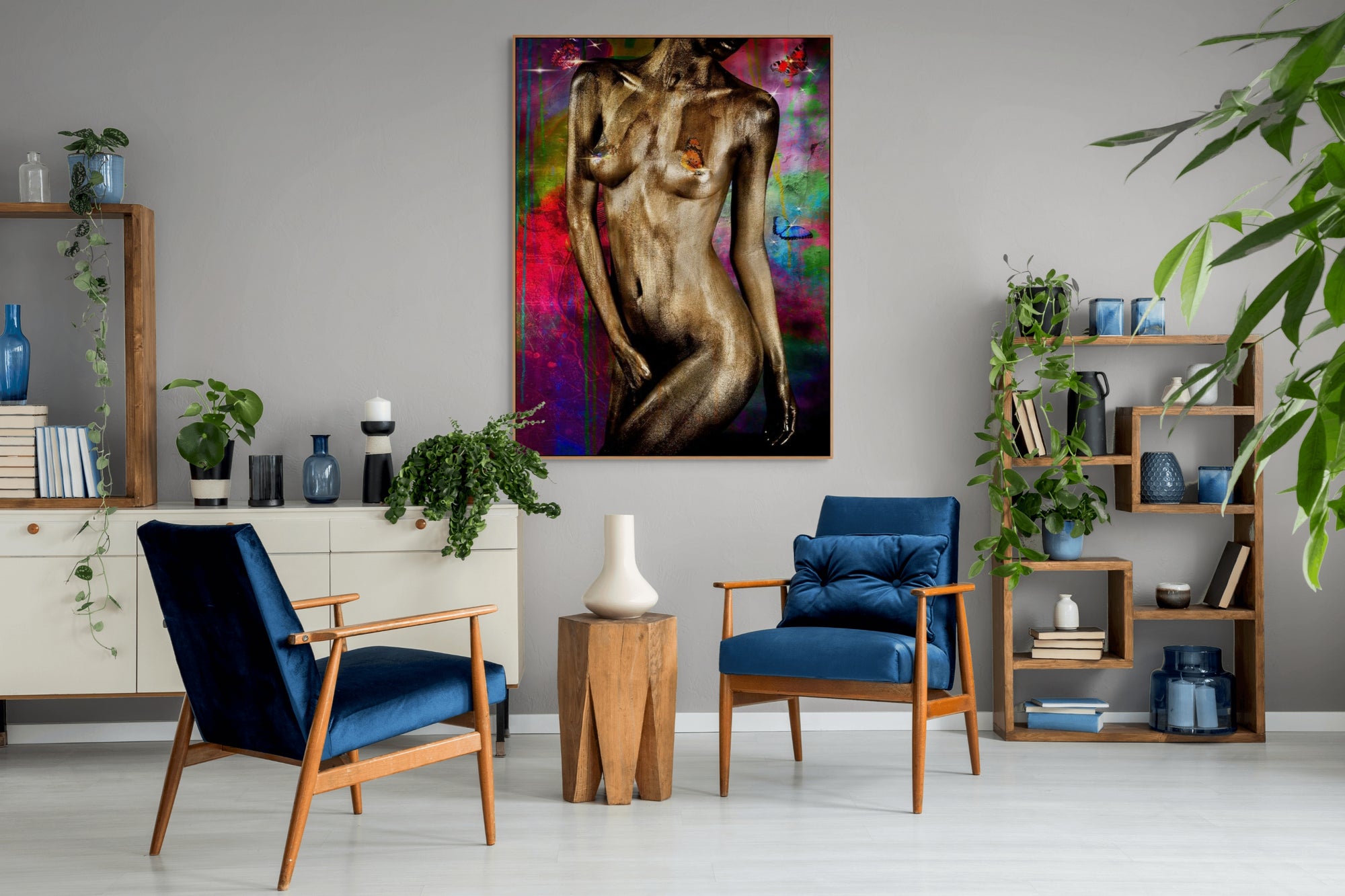 Golden-painted figure artwork with butterflies and vibrant colorful background, displayed in a stylish living room with blue chairs and modern wooden furniture.