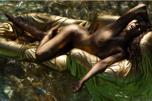 Golden-painted figure reclining on a shimmering gold float in the water, radiating grace and opulence in luxury fine art photography by Zack Zublena.