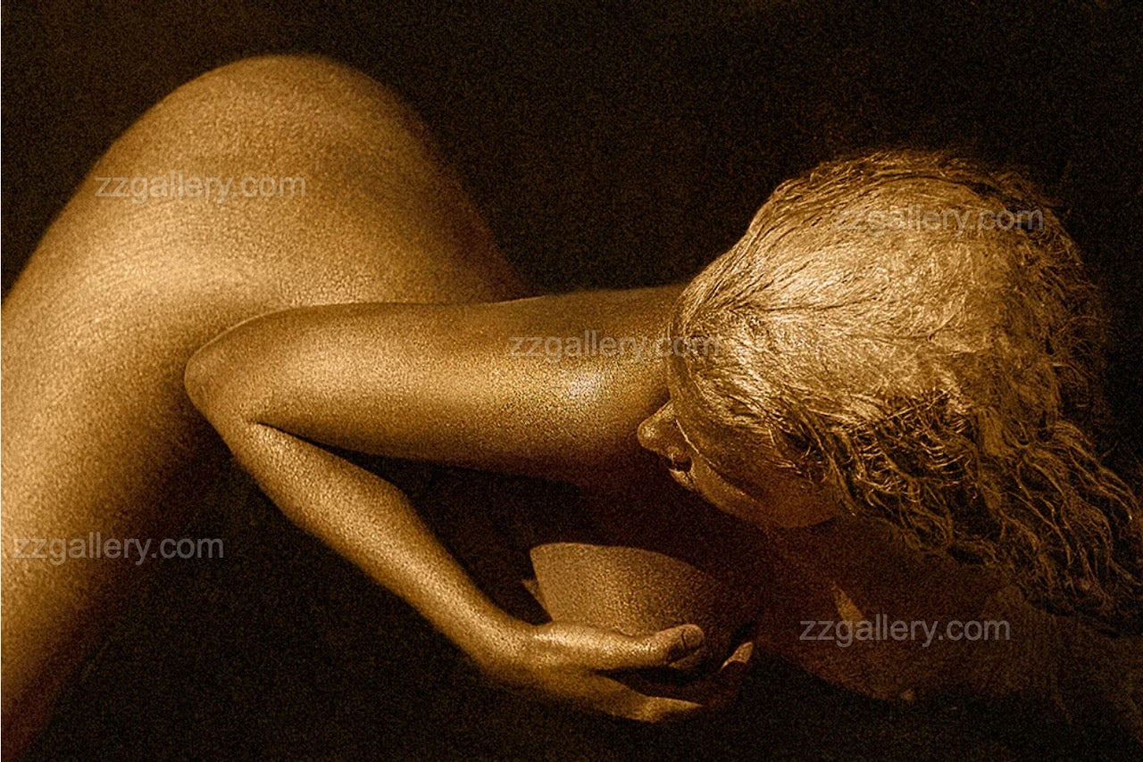 Golden-painted figure captured from above in a fluid curved pose, symbolizing graceful flow, inner harmony, and feminine essence.