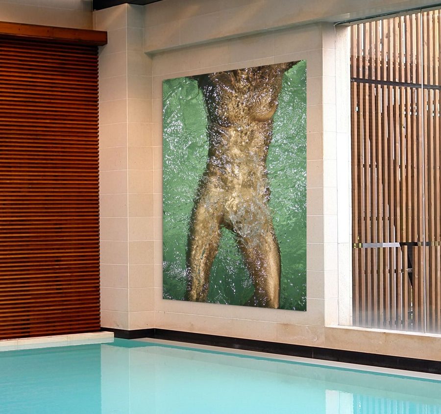 Golden-painted figure body captured underwater in fine art photography, shimmering through flowing water in a swimming pool, symbolizing purity, renewal, and transformation.