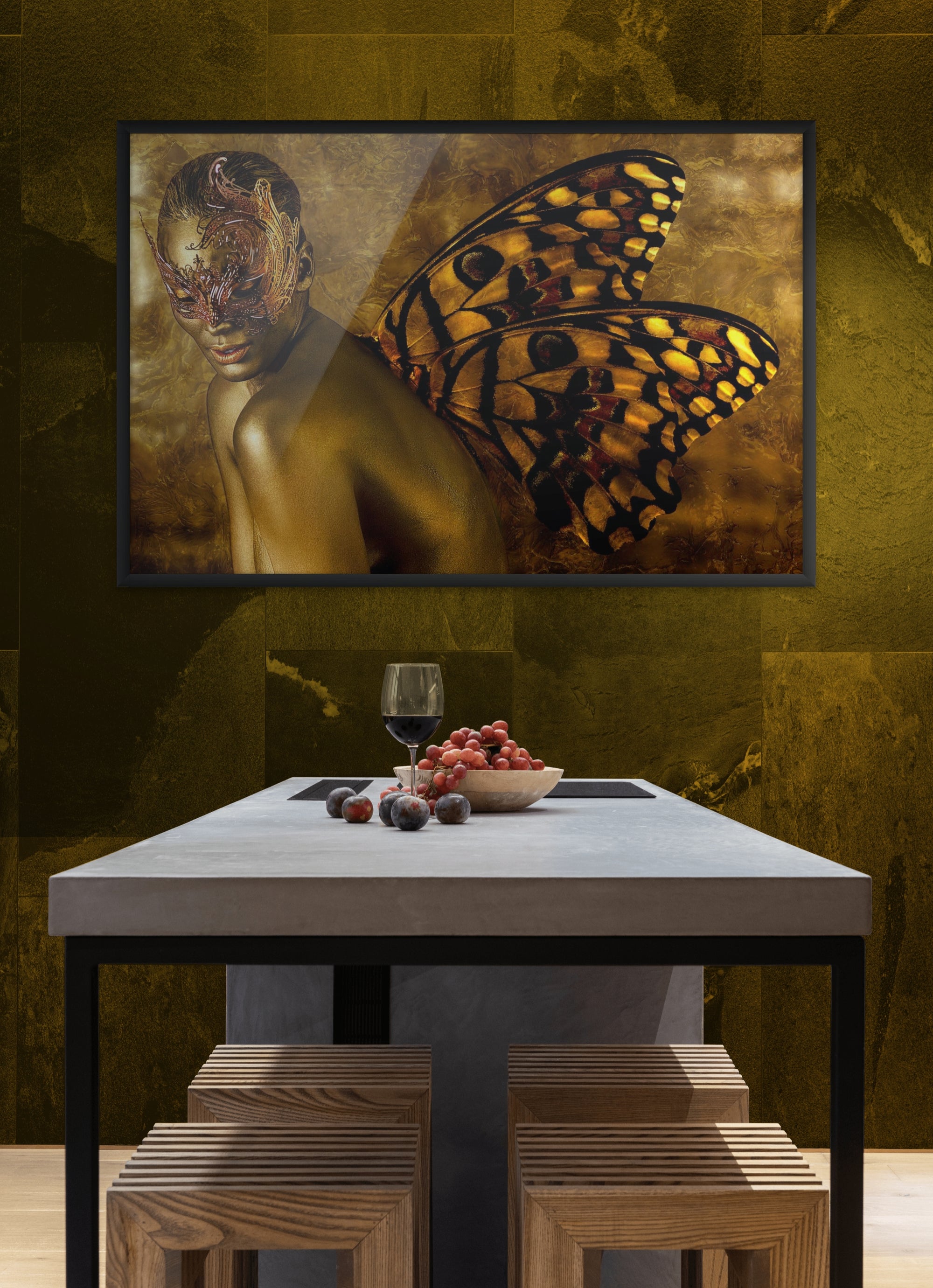 Framed surreal wall art of a gold-painted figure with butterfly wings and ornate mask, displayed on a golden wall above a modern dining table.