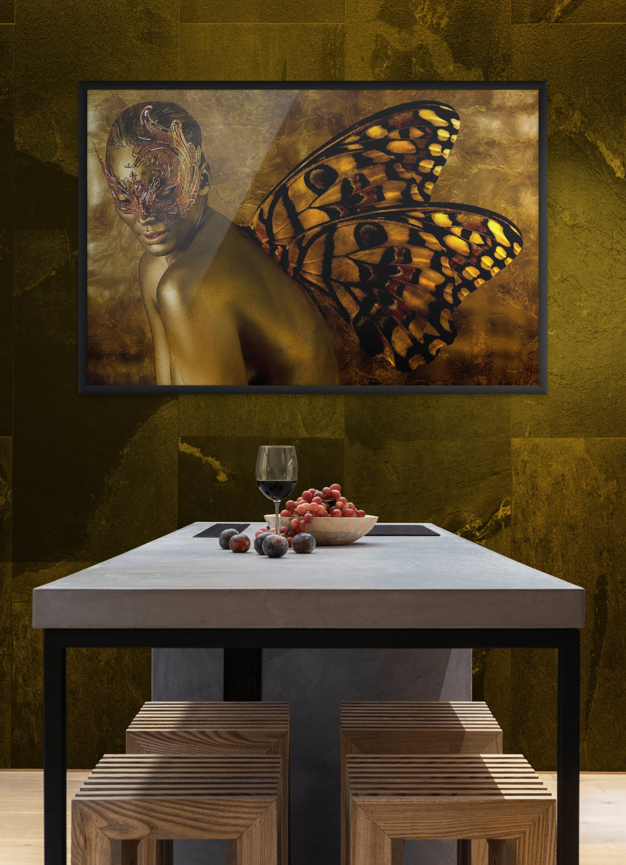 Framed surreal wall art of a gold-painted figure with butterfly wings and ornate mask, displayed on a golden wall above a modern dining table.
