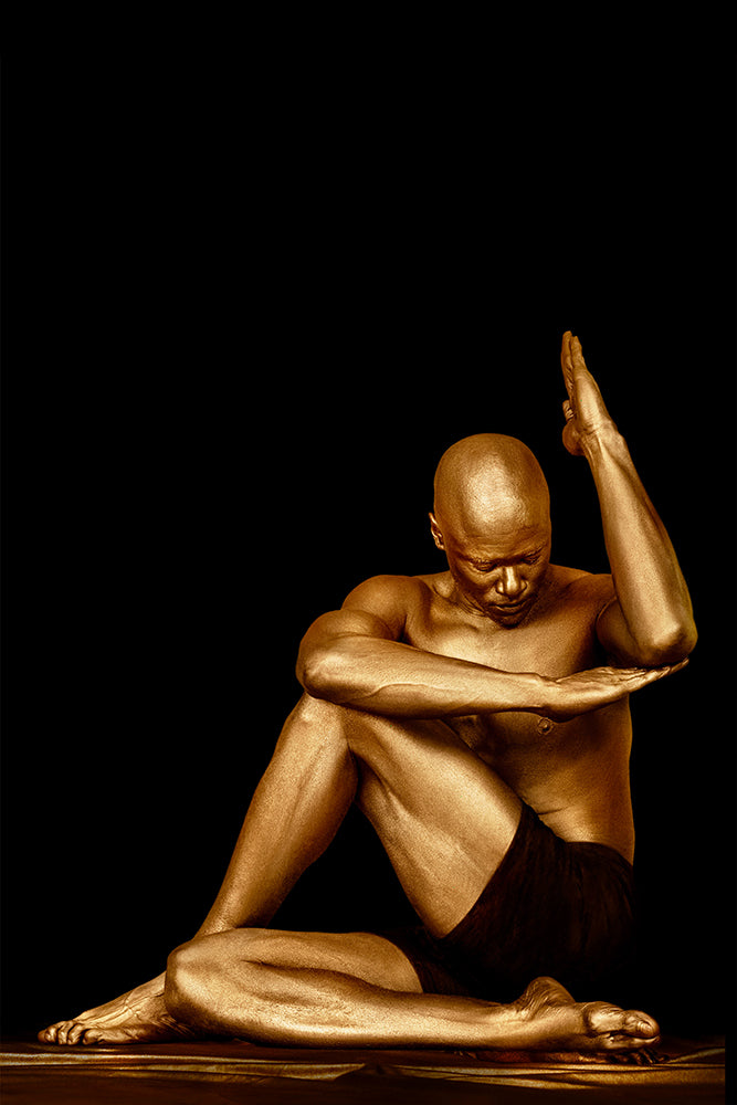 Golden-painted male yogi in seated twist with lifted hand and bowed head – spiritual fine art wall photography